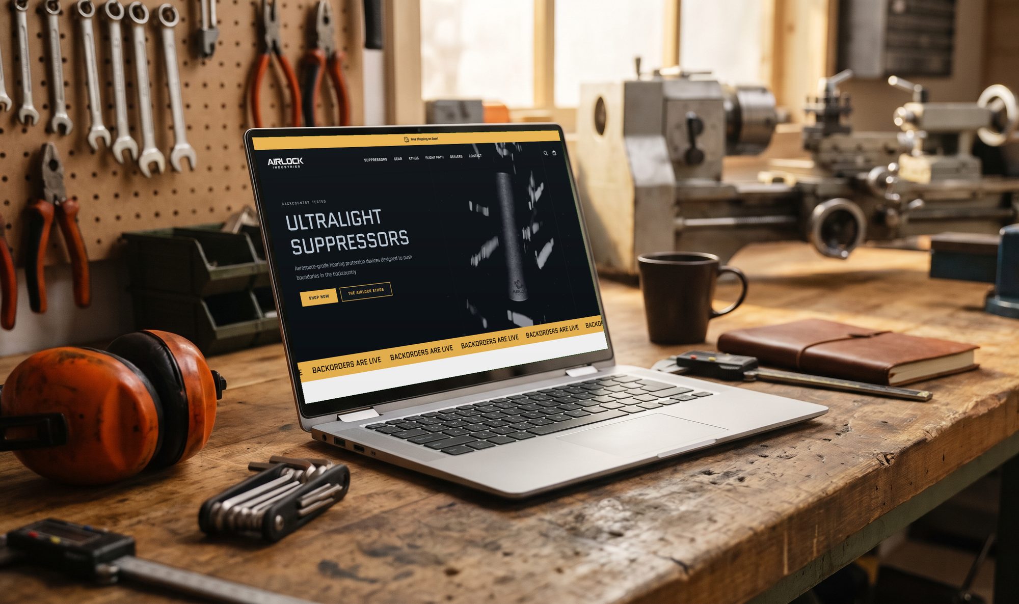 The Airlock Industries homepage on a laptop sitting on a wooden workshop bench